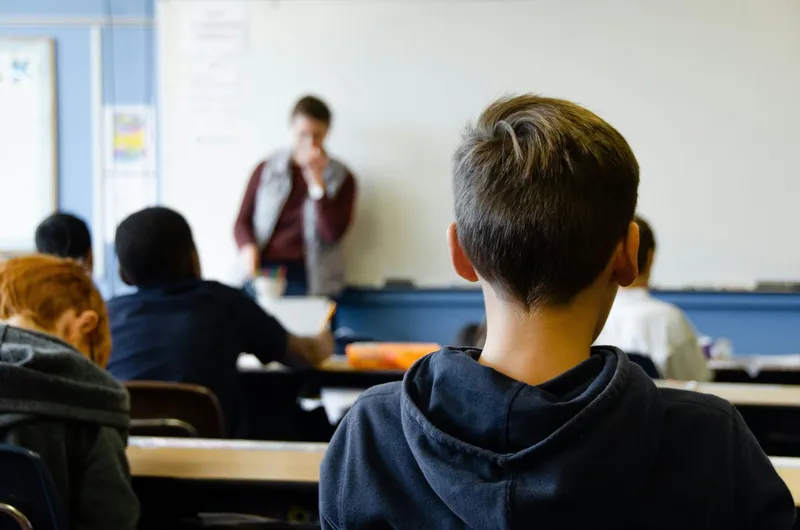 Alumnos en un aula atendiendo a un profesor