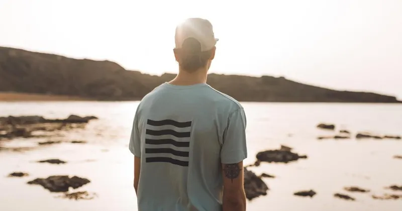 Chico de espaldas con una camiseta de Menorca Republic mirando al mar