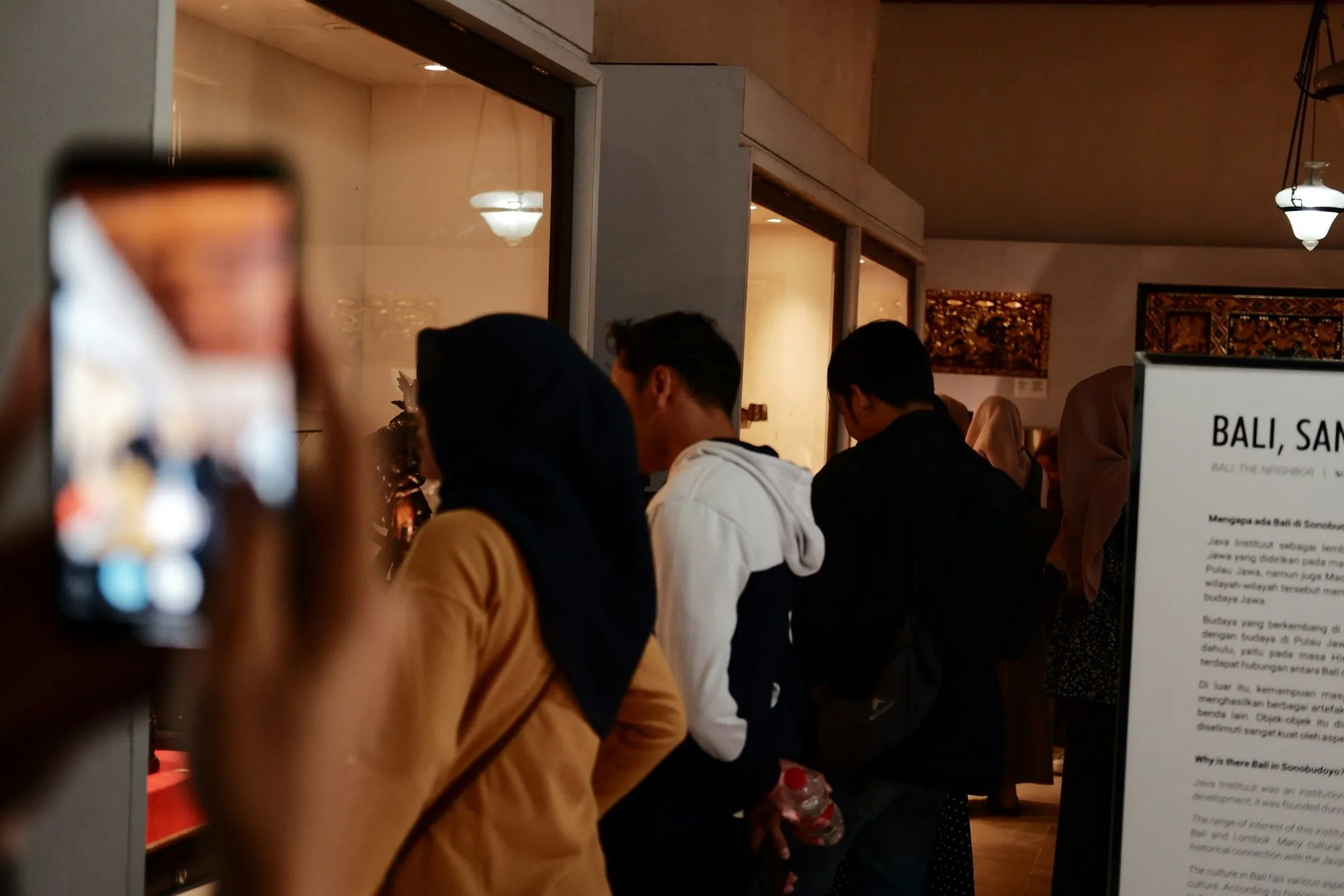 Visitantes en una tienda-exposición; uno de ellos hace una foto con el móvil